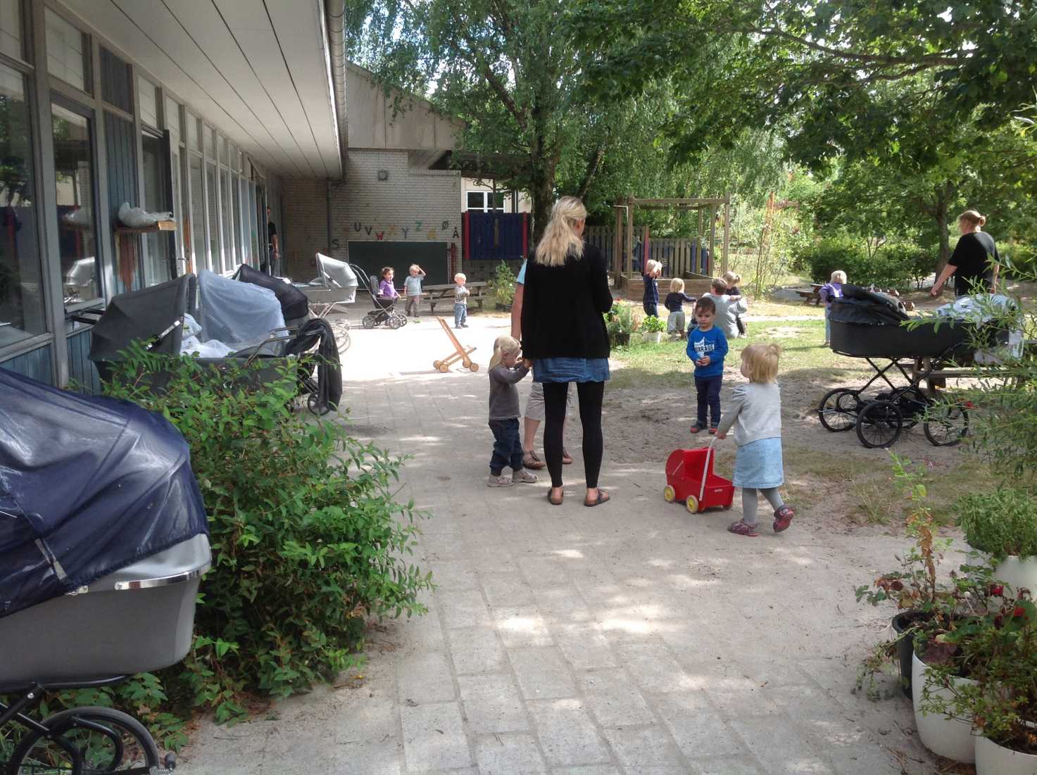 Børn og voksne på legepladsen i Børnehuset Mælkevejen