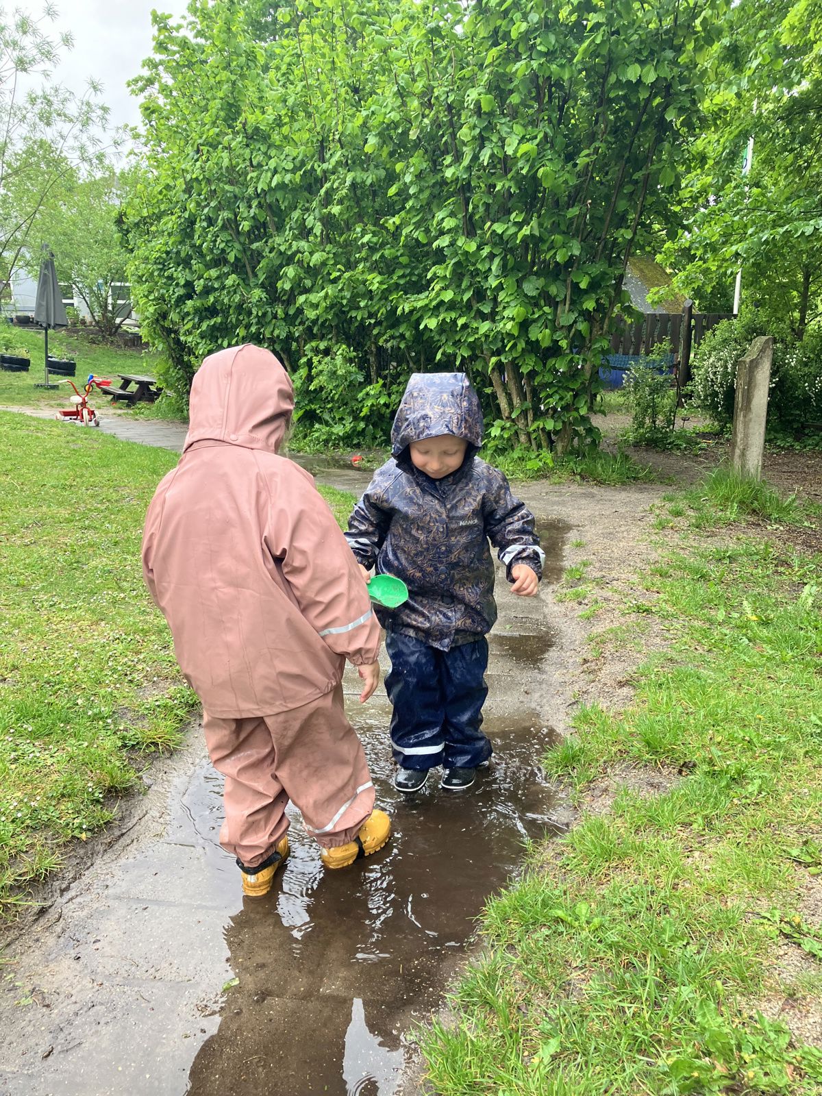 Børn i regnvejr på legepladsen i Børnehuset Mælkevejen